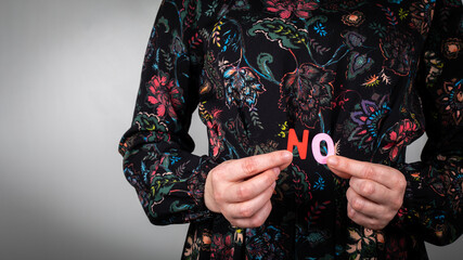 Fototapeta premium Word NO from wooden letters in a woman's hand. White background