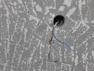 One hole for an electrical outlet with wires on a freshly putty wall. Modern textured putty.