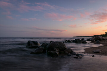 Fototapeta na wymiar rocky sea shore before sunrise, dark stone silhouettes and colorful sky