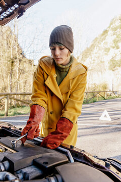 Woman applying clamps on car battery in autumn park
