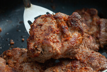 Frying pork meat on the pan, closeup