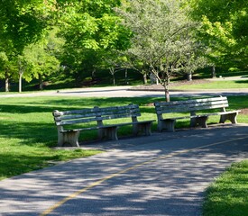 The park benches on the pathway at the park.