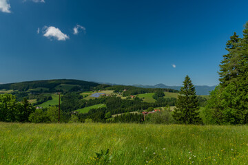 Pass near Niederer Schockl hill with green meadows and fences in Austria