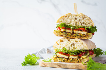Vegetarian sandwich with grilled vegetables, halloumi cheese and ciabatta on board, white...