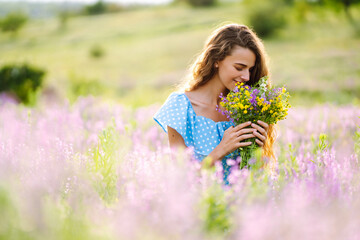 Naklejka na ściany i meble Portrait of beautiful woman in amazing in a blooming field. Nature, vacation, relax and lifestyle. Summer landscape.