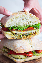Vegetarian sandwich with grilled vegetables, halloumi cheese and ciabatta in hands. Comfort food concept.