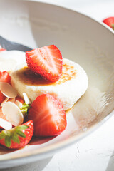 Homemade cottage cheese fritters - syrniki with strawberries and yogurt, Russian and Ukrainian cuisine concept.