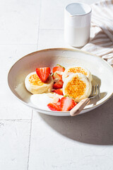 Homemade cottage cheese fritters - syrniki with strawberry and yogurt. Russian and Ukrainian cuisine concept.