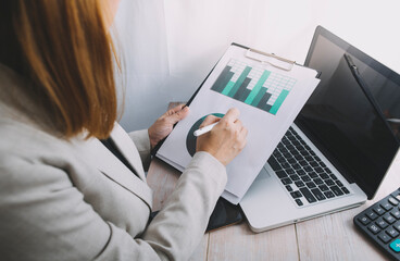 Businesswomen hands working with finances about cost and calculator and laptop with tablet, smartphone at office in morning light