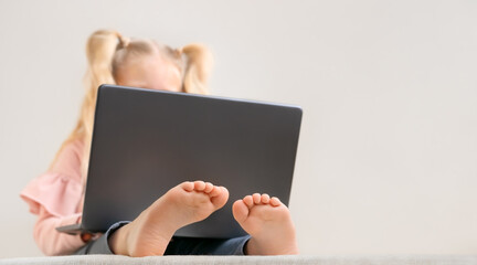 Little girl with laptop, only top of the blonde head and little feet are visible