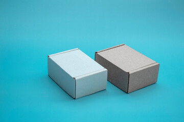 Close-up mock-up of cardboard boxes with copy space. Two corton boxes: brown and white on a blue...