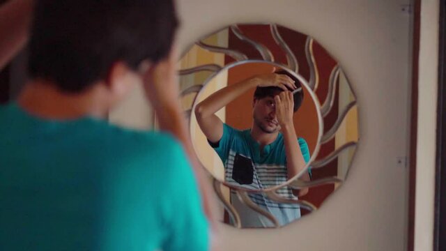 Indian man combing his hair while looking in the mirror, Selective focus on the mirror. Indian Man getting ready to go outside