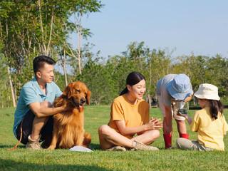 Happy family of four and pet dog playing in the park