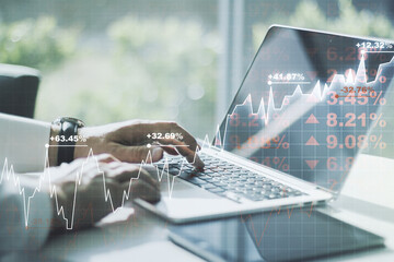 Multi exposure of abstract creative financial graph with hand typing on laptop on background, forex...