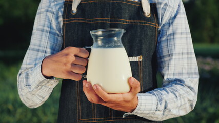 The farmer holds a jug with milk. Organic products concept