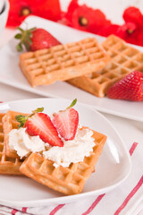 Waffles with strawberries and whipped cream.