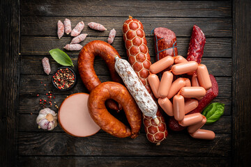 Set of different types of sausages, salami and smoked meat with basil and spices on wooden...