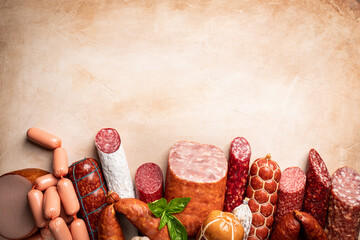 Set of different types of sausages, salami and smoked meat with basil and spices on light...