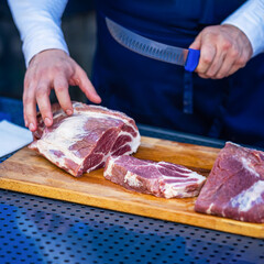 Male hands of seller with knife cutting slices from Raw beef for steaks in meat store, in supermarket