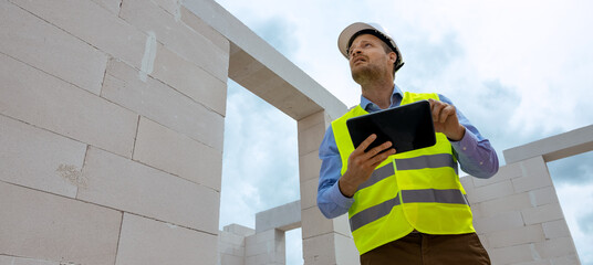 construction project monitoring - engineering supervisor working with digital tablet at building...