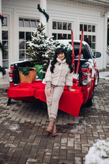 Woman sitting on the back of a pickup, loaded with Christmas things