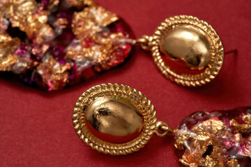 Close up shot of epoxy resin earrings with golden foil inside isolated over red background