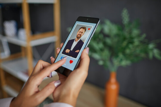 Selective focus woman finger swiping liking profile on relationship site pushing heart icon on screen to find love in mobile smartphone application. Online dating app, valentines day concept.