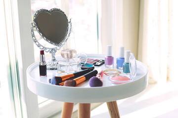 Set of makeup cosmetics with brushes and mirror on table