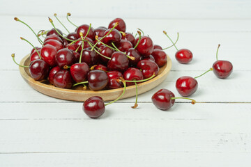 Naklejka na ściany i meble Red sweet cherry berries on a plate on white wooden table.