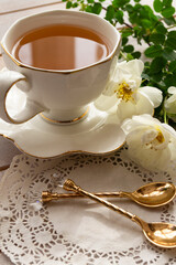 cup of tea with little roses on white wooden table