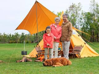 Happy grandparents and grandchildren take a group photo with their pet dog outdoors
