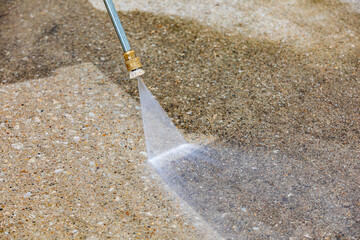 Pressure washing concrete driveway. Home cleaning, maintenance and household chores concept - obrazy, fototapety, plakaty