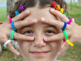 portrait of teenage girl with colorful elastic bands on her fingers and rainbow hair clips, LGBTQ...