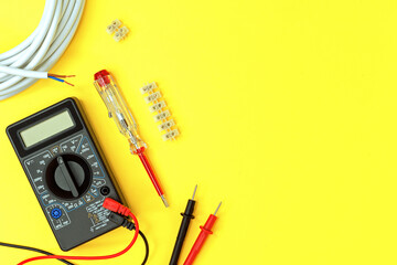 Digital multimeter and indicator screwdriver on a yellow background. Voltmeter, ohmmeter, ammeter.