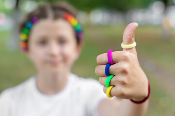 girl with colorful elastic bands on her finger show thumb up symbol everything is ok, LGBTQ theme