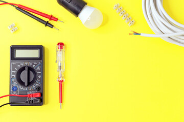 Digital multimeter and indicator screwdriver on a yellow background. Voltmeter, ohmmeter, ammeter.