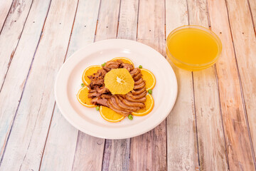 typical Chinese recipe of fried duck sliced with orange on a white porcelain plate and bowl with lots of orange sauce