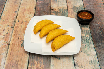 Ration of Colombian cornmeal empanadas stuffed with meat and sauce for dipping