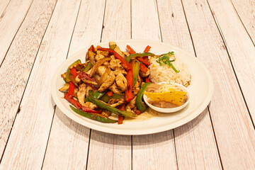 Plate of Mexican chicken fajitas with sautéed peppers, rice and chipotle