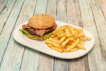 Classic beef burger with cheese, lettuce and bacon and guranicion of French fries