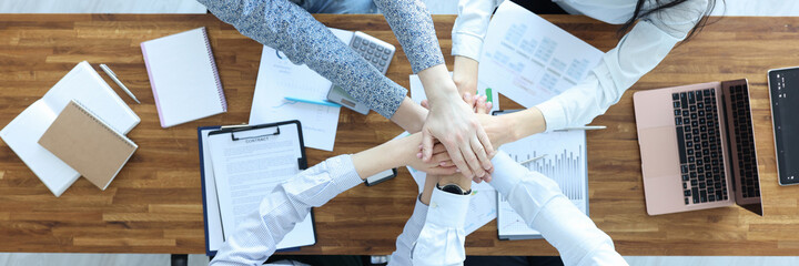 Businessmen and businesswoman at working table hold their hands together