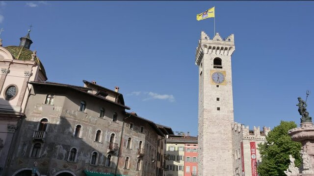 Trento, Italy, June 2021. Beautiful pan footage of the main square: overlook the historic buildings with the frescoed facade, the bell tower, the fountain of Neptune and the cathedral. Nice sunny day.