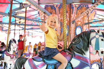 Fototapeta na wymiar Happy Little Child On Merry Go Round Horse at Carnival
