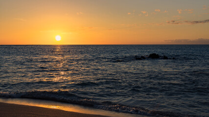 Fototapeta na wymiar A bright orange sunset from a tropical beach. 