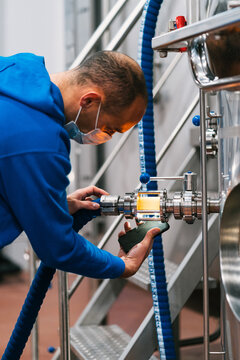 Engineer with smartphone examining filter tube in brewery