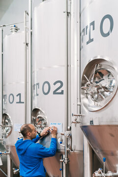 Entrepreneur writing on paper on fermentation tank in brewery
