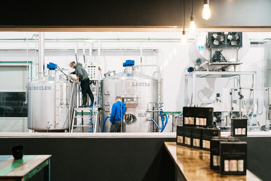 Unrecognizable coworkers examining professional equipment in beer factory - Powered by Adobe