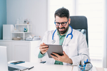 Smiling physician with tablet during video call in clinic
