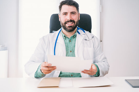 Smiling doctor in uniform with paper at work in hospital