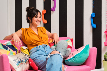 Cheerful woman sitting on colorful sofa with cushions